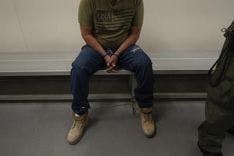 Detained man sitting with hands intertwined